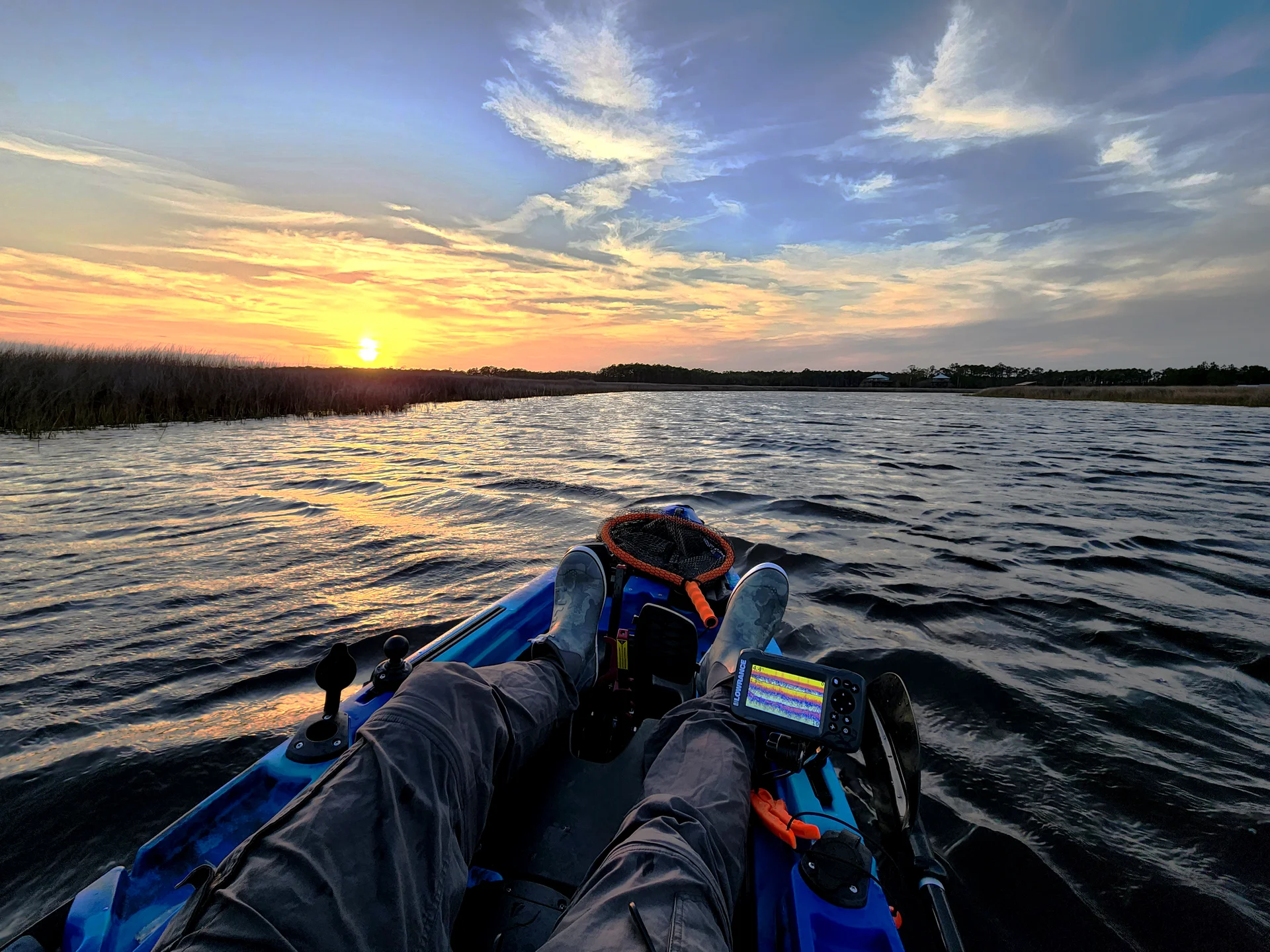 View from the cockpit of a fishing kayak on a marsh creek at sunset